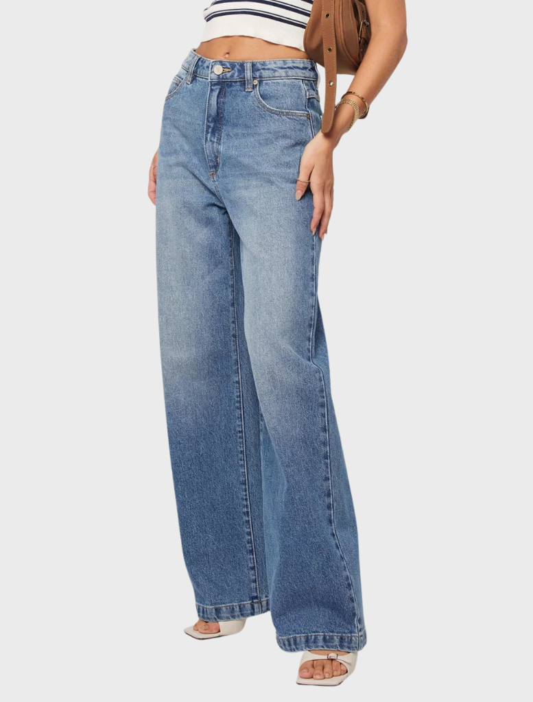 A woman dressed in wide-legged jeans and a striped top poses, highlighting a trendy and comfortable ensemble.