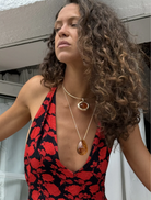 A gold necklace displaying a large orange stone, combining sophistication with a pop of color.