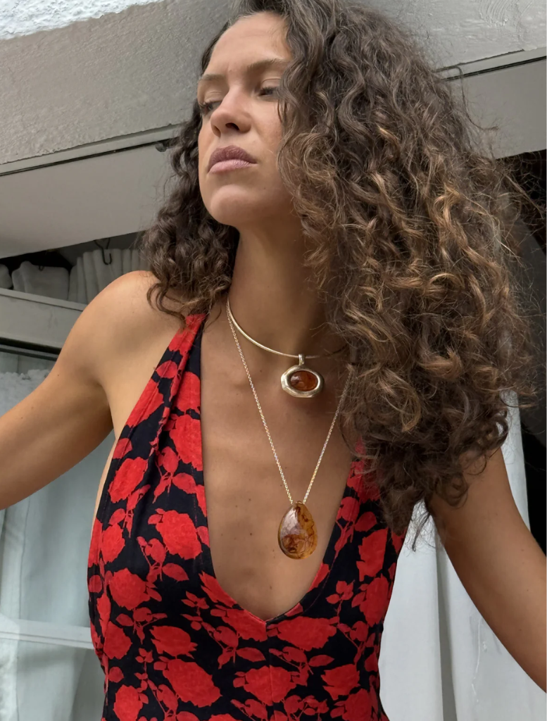 A gold necklace displaying a large orange stone, combining sophistication with a pop of color.