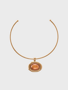 A gold necklace featuring a prominent orange stone at its center, elegantly designed for a striking appearance.