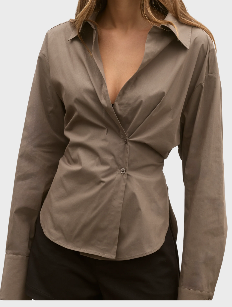 The model showcases a brown shirt paired with shorts, standing in a relaxed pose with a neutral backdrop.