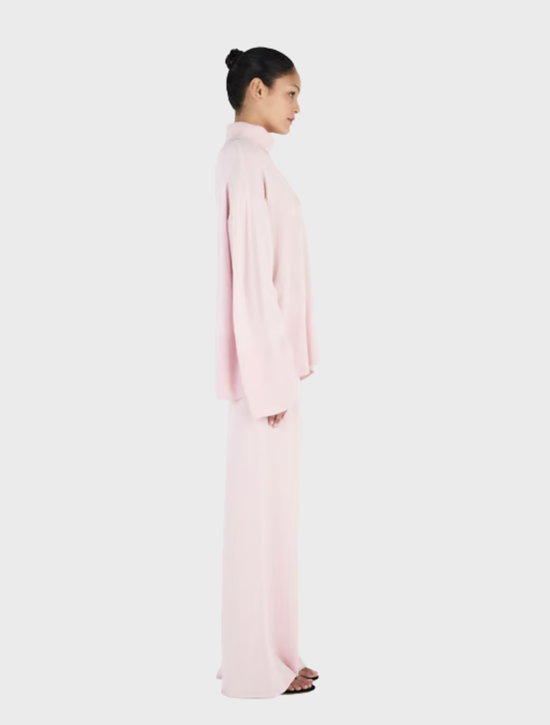 A blush-colored Bay Cashmere Jumper draped elegantly, highlighting its luxurious fabric and stylish silhouette.
