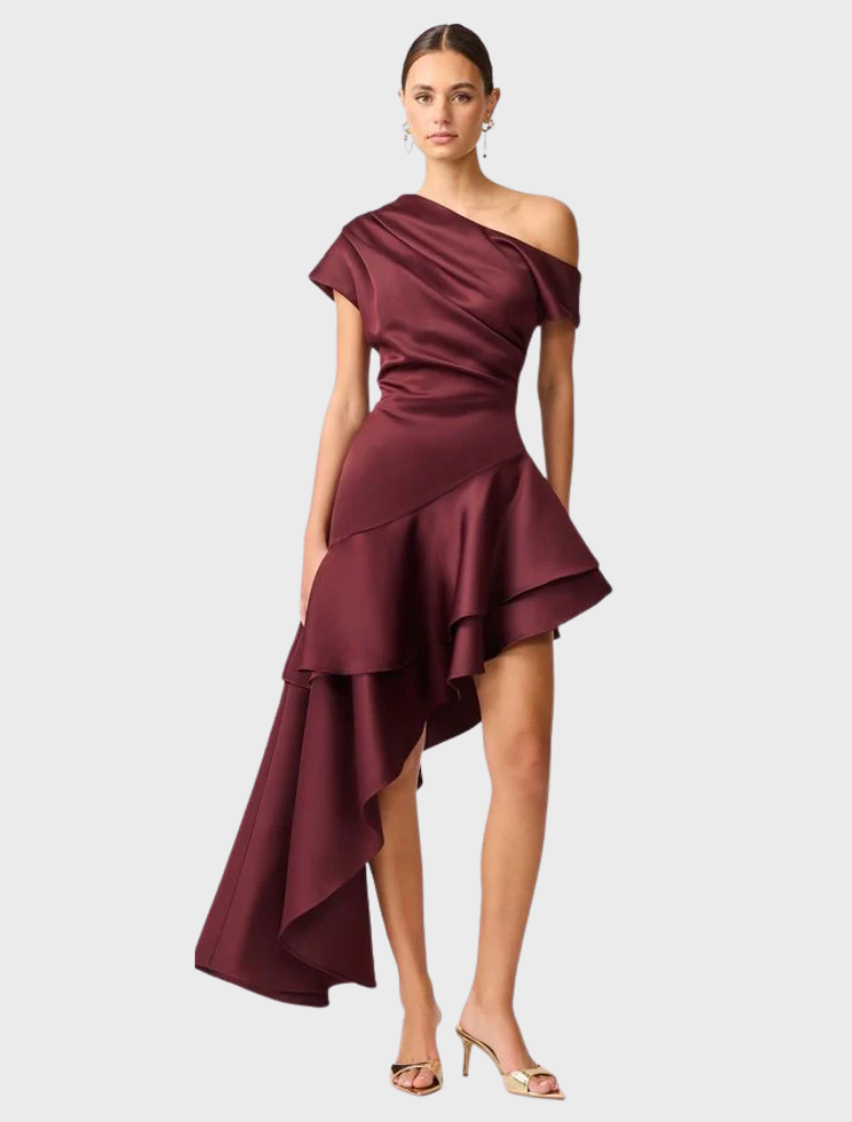 Livia Gown in berry satin features an asymmetric hem, offering a stylish and modern silhouette.