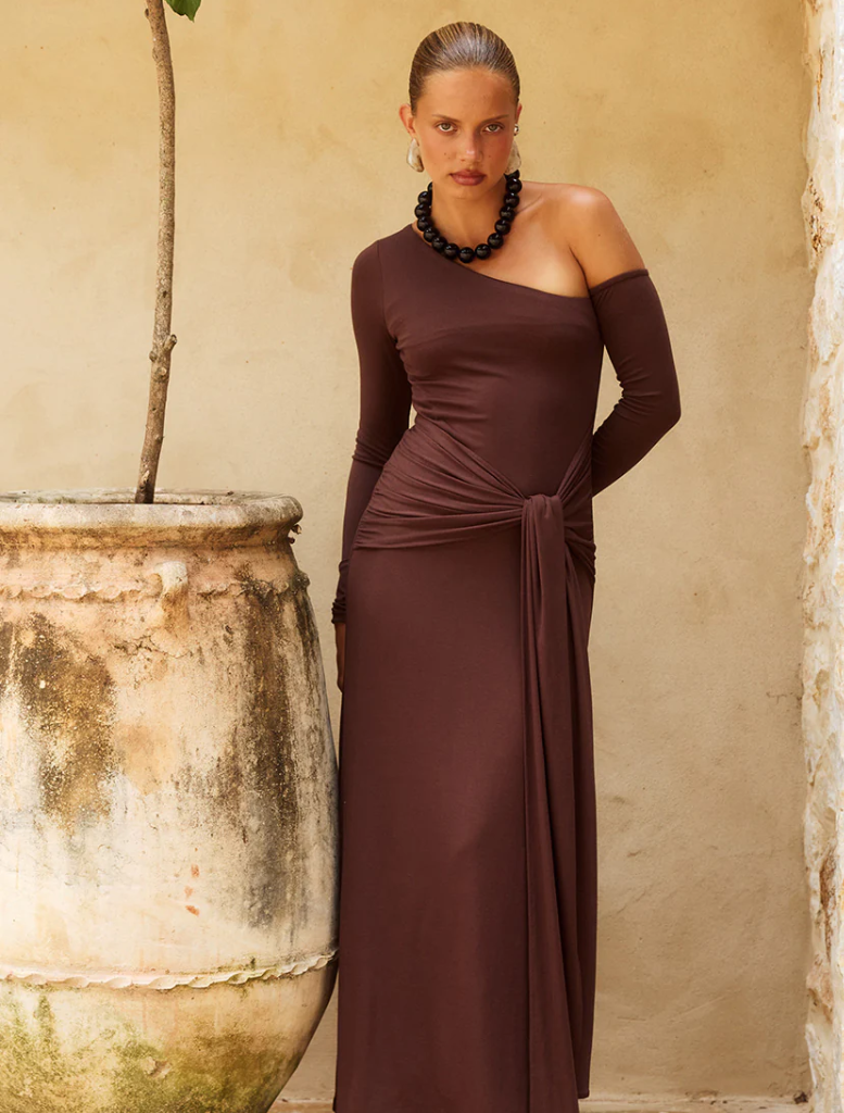 Chocolate-colored one-shoulder maxi dress, featuring a flowing silhouette and elegant design suitable for formal occasions.