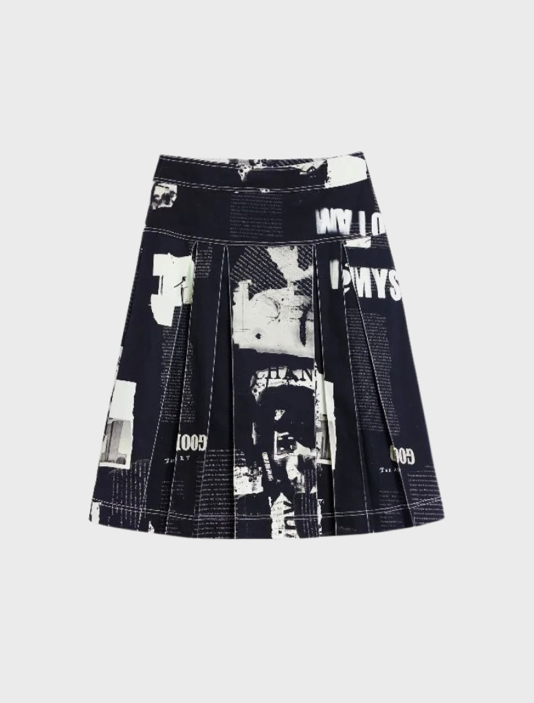 The image features a model in a black and white print jacket and skirt, showcasing the Newspaper Pleated Midi Skirt in black.