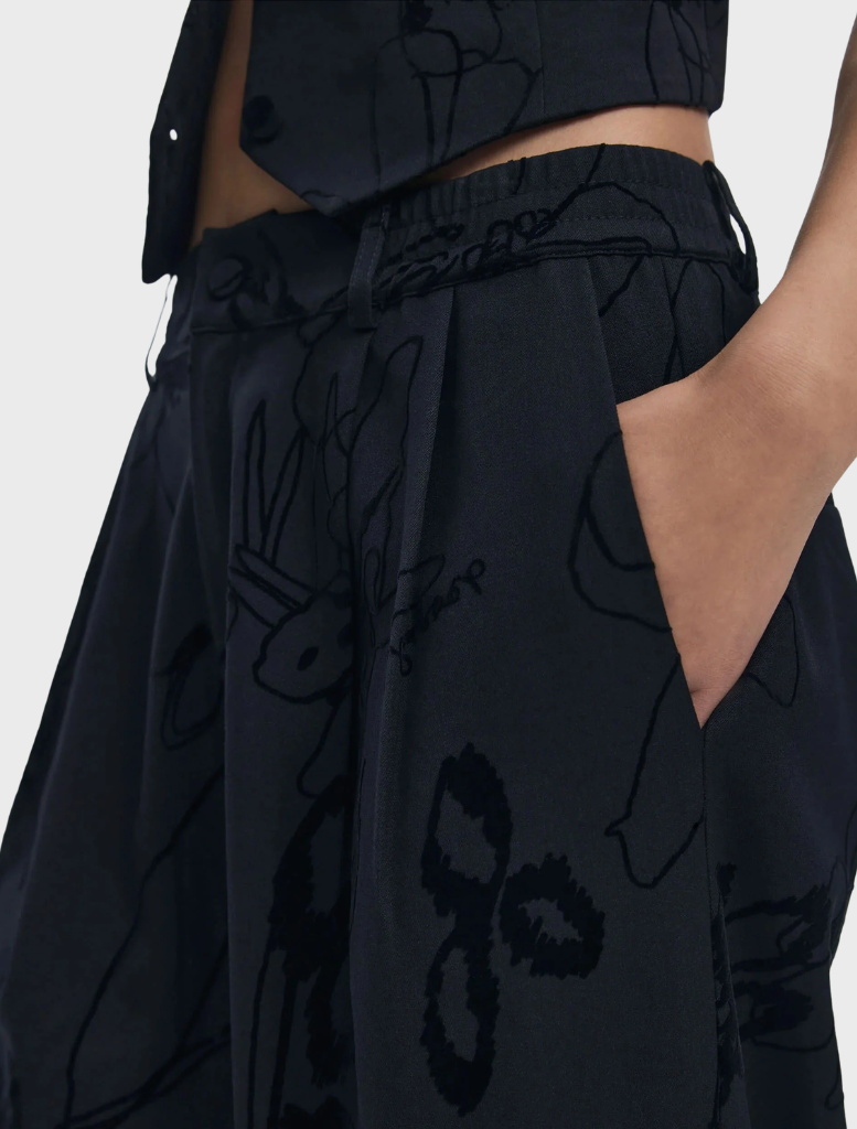 A close-up of black long trousers, illustrating their smooth fabric and tailored silhouette for a polished look.