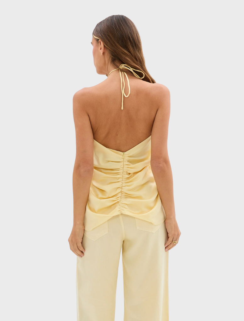 A model wears pale yellow Celeste Jean Pants along with a top, exemplifying a chic and trendy ensemble.