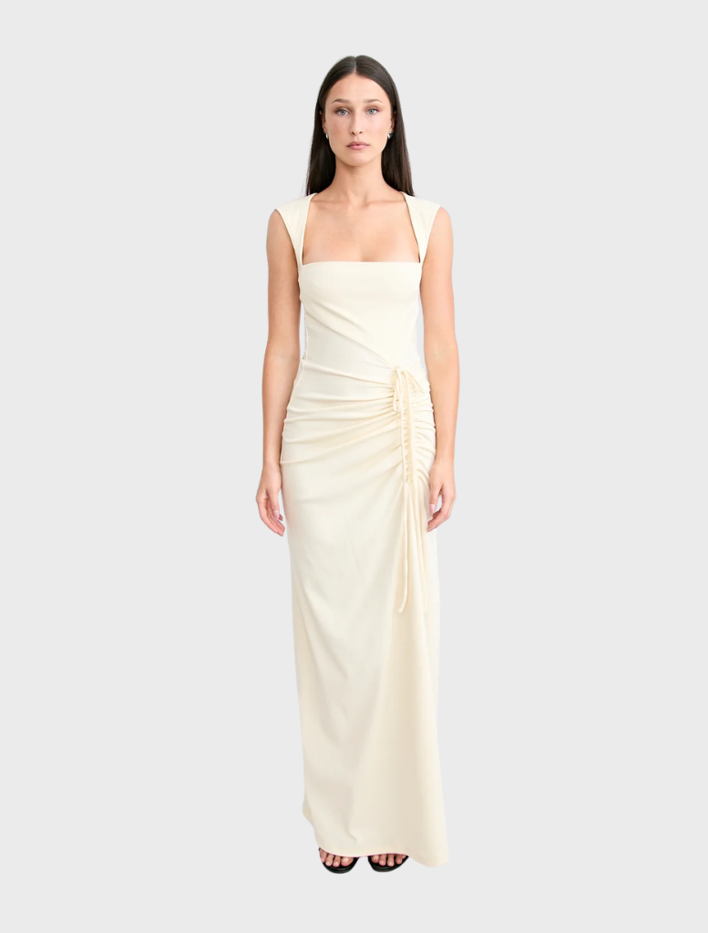 The Samara gown in butter showcases a graceful design with a light, airy fabric perfect for formal occasions.