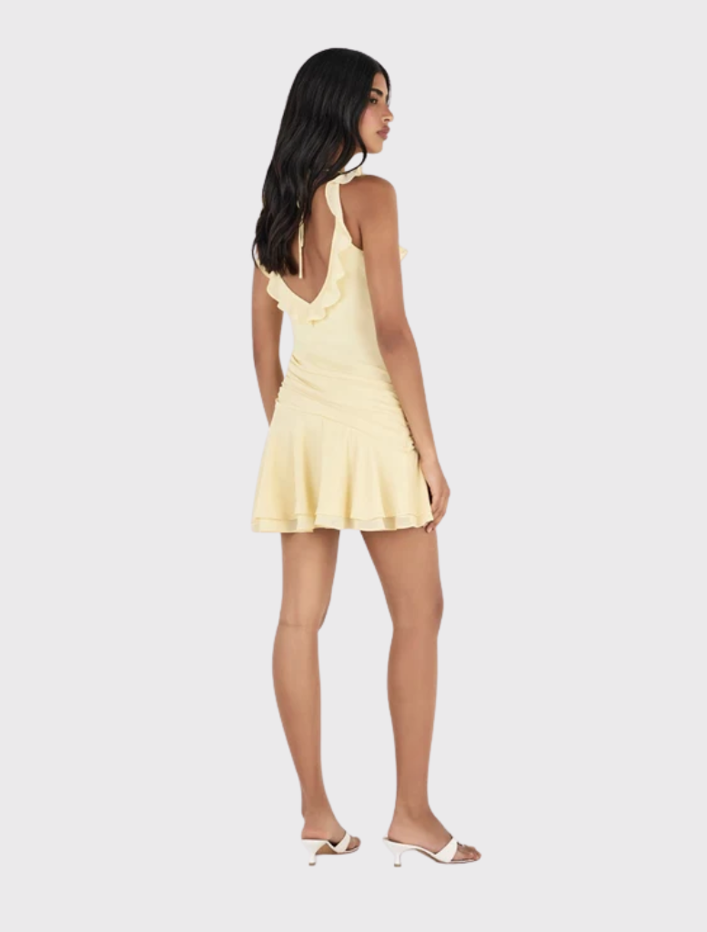 Fitted mini dress in butter yellow with ruffles, deep V neckline, open back, and asymmetrical draped panel.