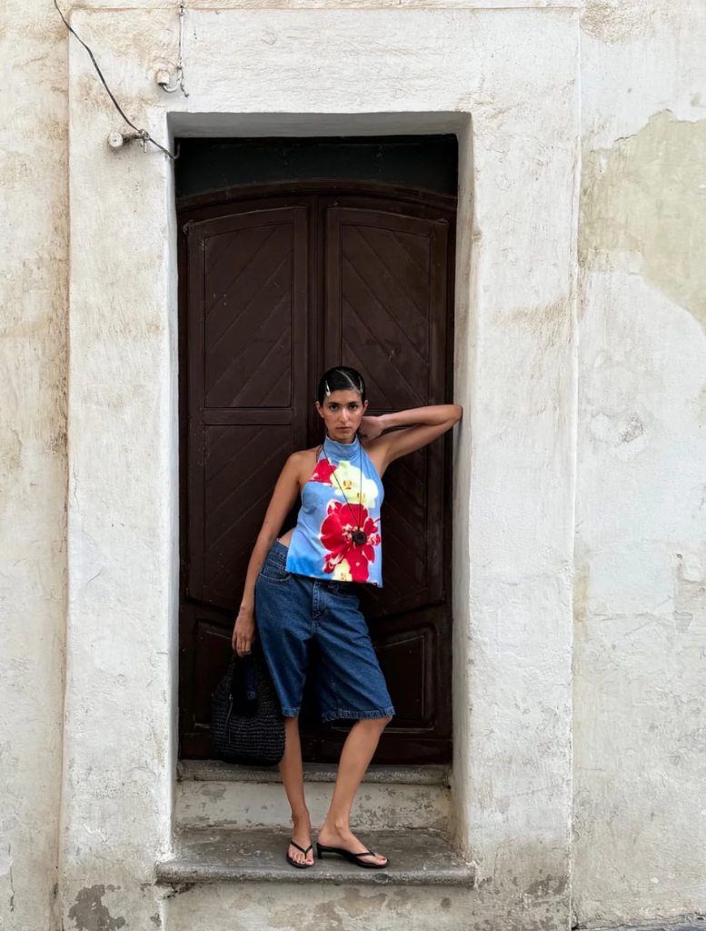 woman wearing a floral top and skirt poses for a selfie, capturing her cheerful expression.