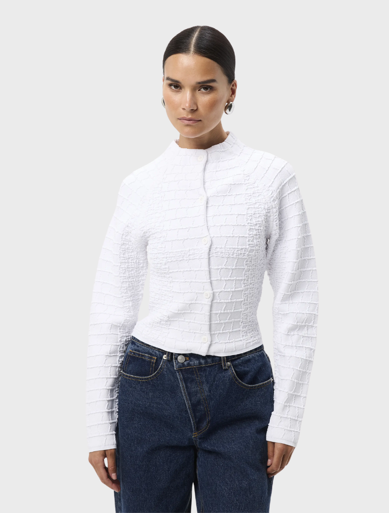White Carter Cardigan displayed on a hanger, featuring a classic design with long sleeves and a soft texture.