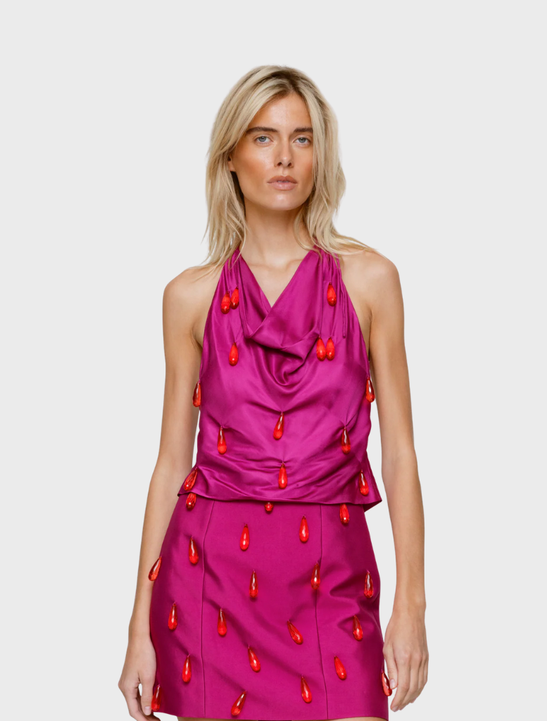 A woman wearing a pink dress carries an orange bag, highlighting a fashionable look with bold color choices.