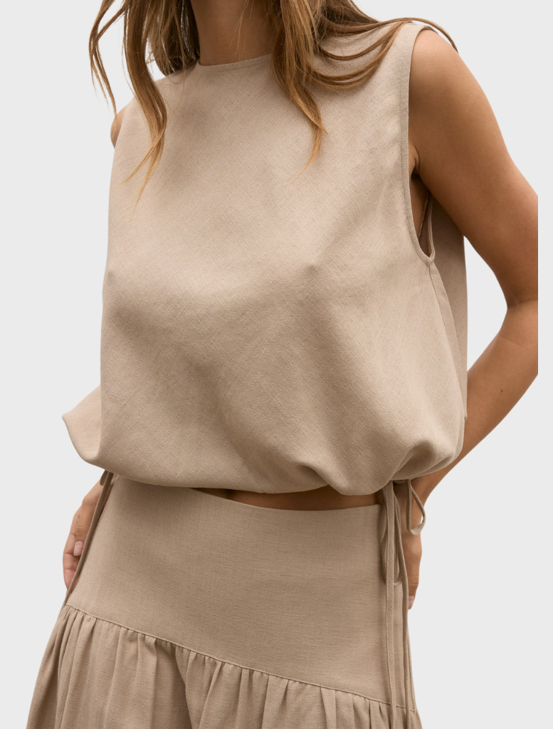 The image features a model in a tan Delphine top and skirt, presenting a fashionable ensemble.