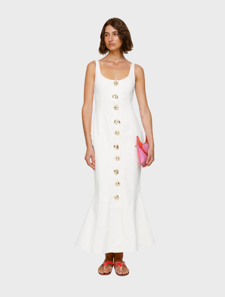 A woman dressed in an ivory Sibel Denim dress and sandals stands confidently, embodying a fresh summer look.