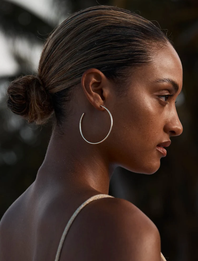 Medium-sized gold hoops with a hammered finish, crafted by Emma Pills, designed for sensitive ears with a stud back closure.