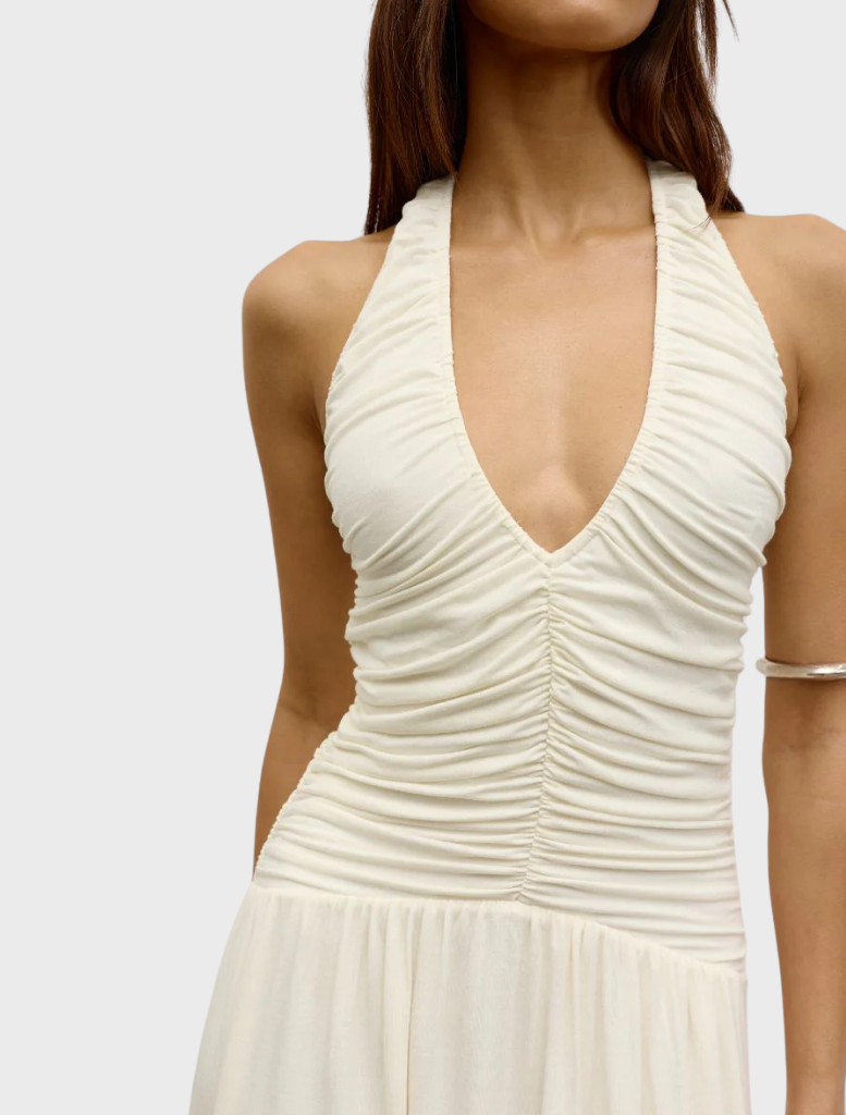 A woman dressed in an ivory Frances dress and sunglasses smiles, radiating a fresh and fashionable summer vibe.