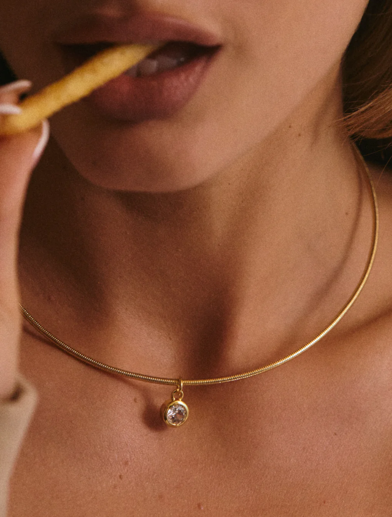Elegant gold choke necklace with a diamond charm, identified as the Georgia Stone Omega Necklace.