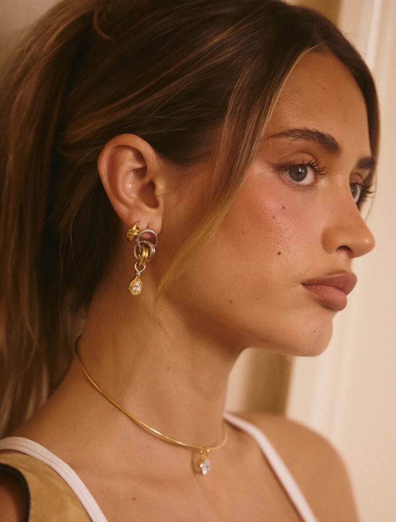 The Georgia Stone Twisted Studs - Gold, featuring two-tone gold and white diamond drop earrings with a stylish twisted design.