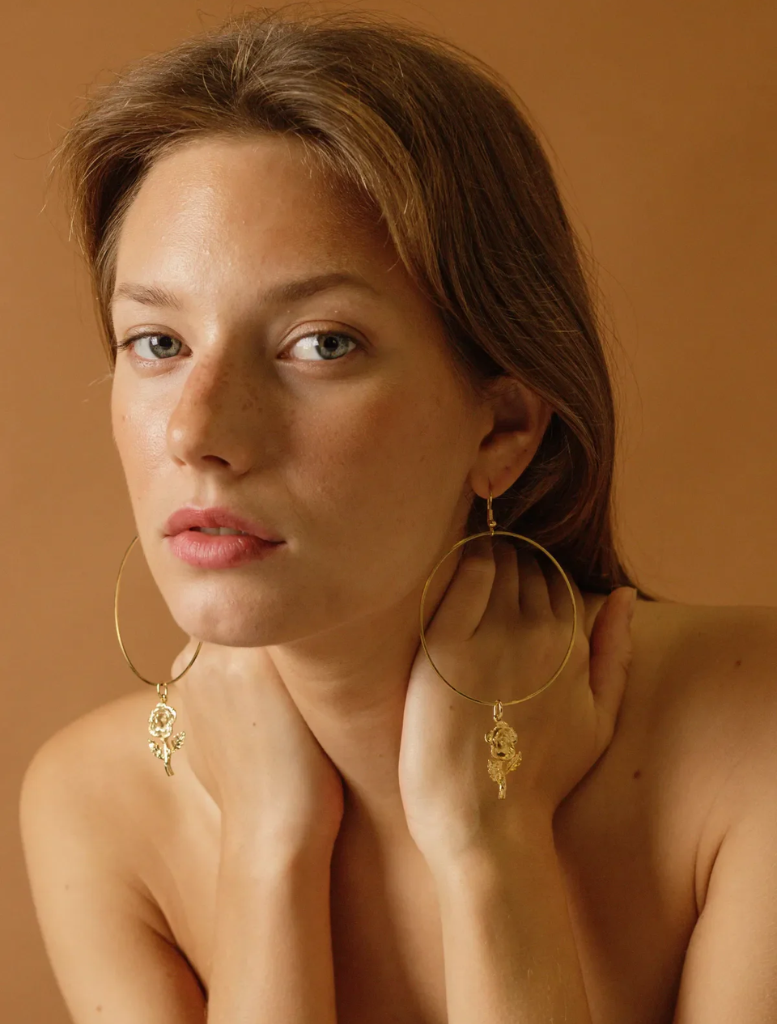 Elegant gold hoop earrings adorned with a rose charm, identified as Rosa Linda Earrings.