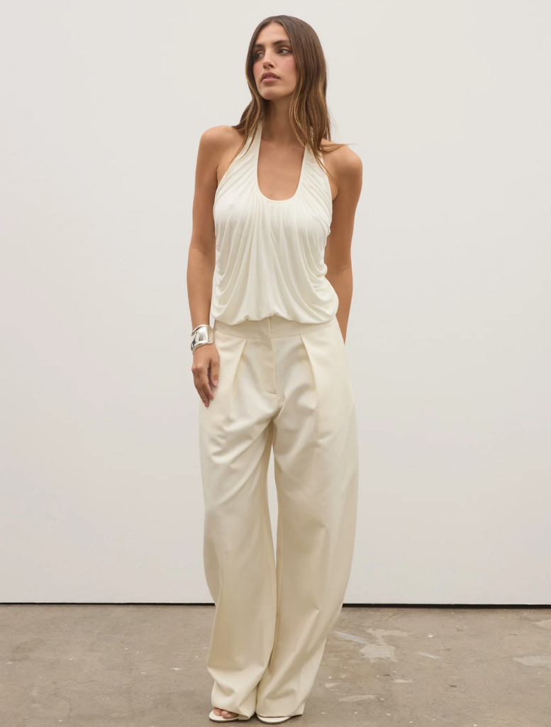 A woman wearing an ivory Lennie top and wide pants stands confidently, showcasing a stylish and relaxed outfit.