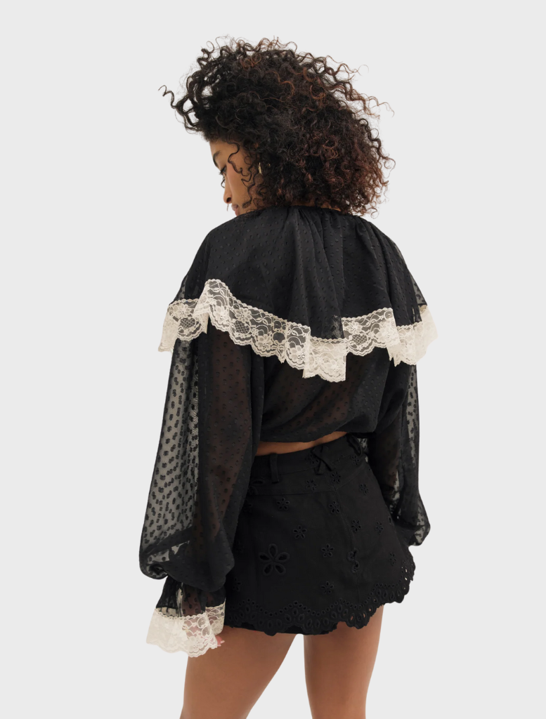 Simple black June top presented on a hanger, emphasizing its classic and adaptable fashion appeal.