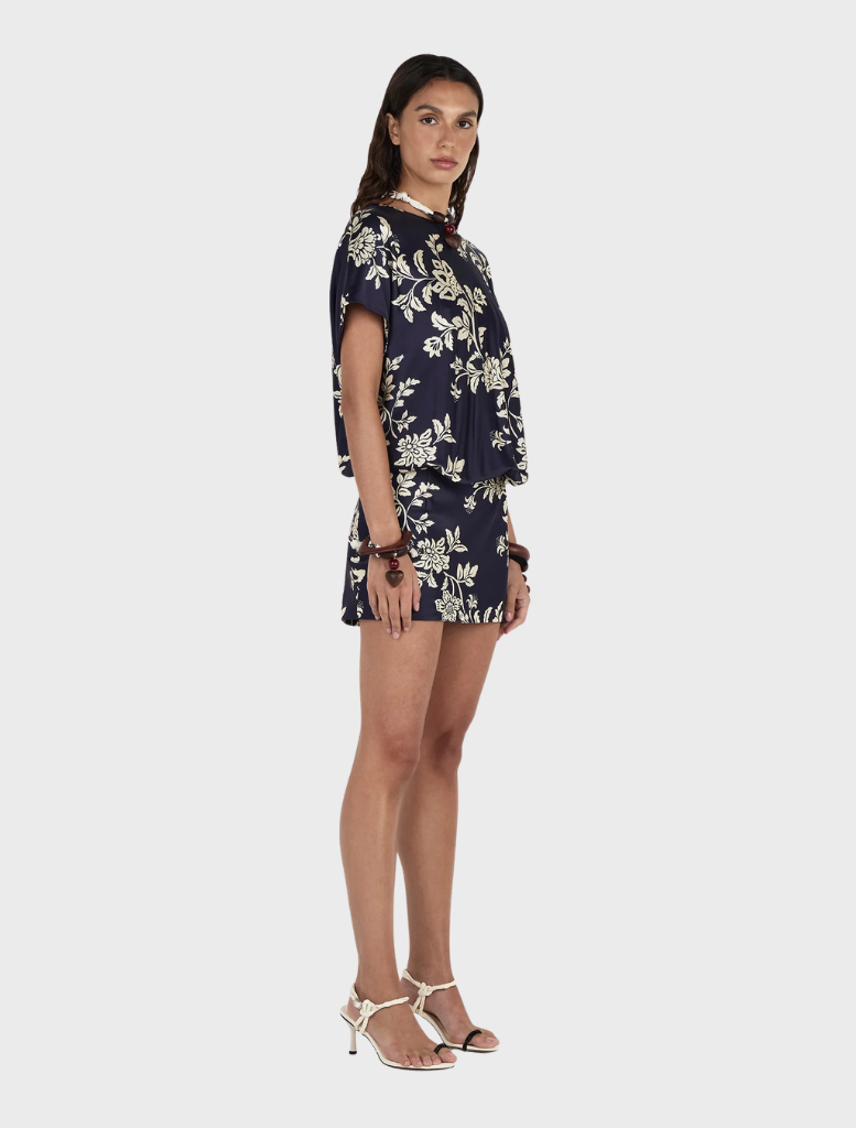 The model showcases the Kodie Mini Dress, featuring a floral print in navy and white.