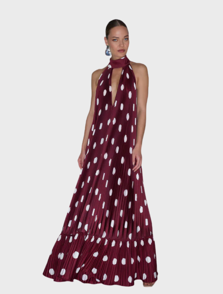 A model showcases a maroon dress adorned with white polka dots, standing confidently against a neutral background.