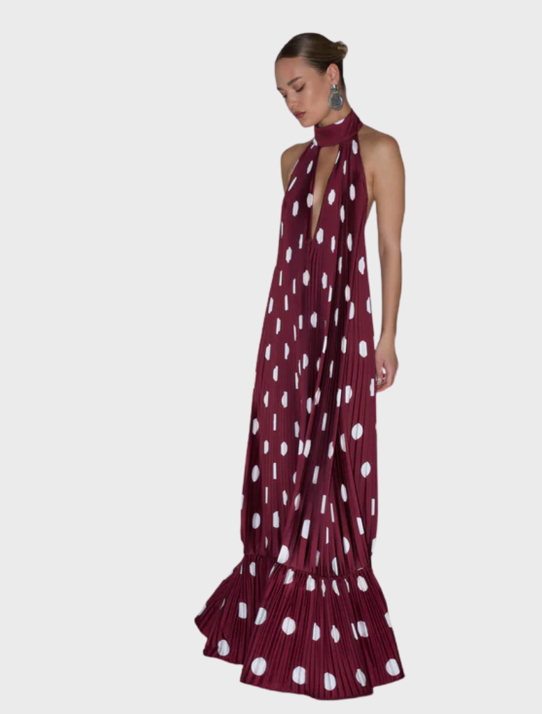A model wears a maroon dress featuring white polka dots, exuding a vintage-inspired style.