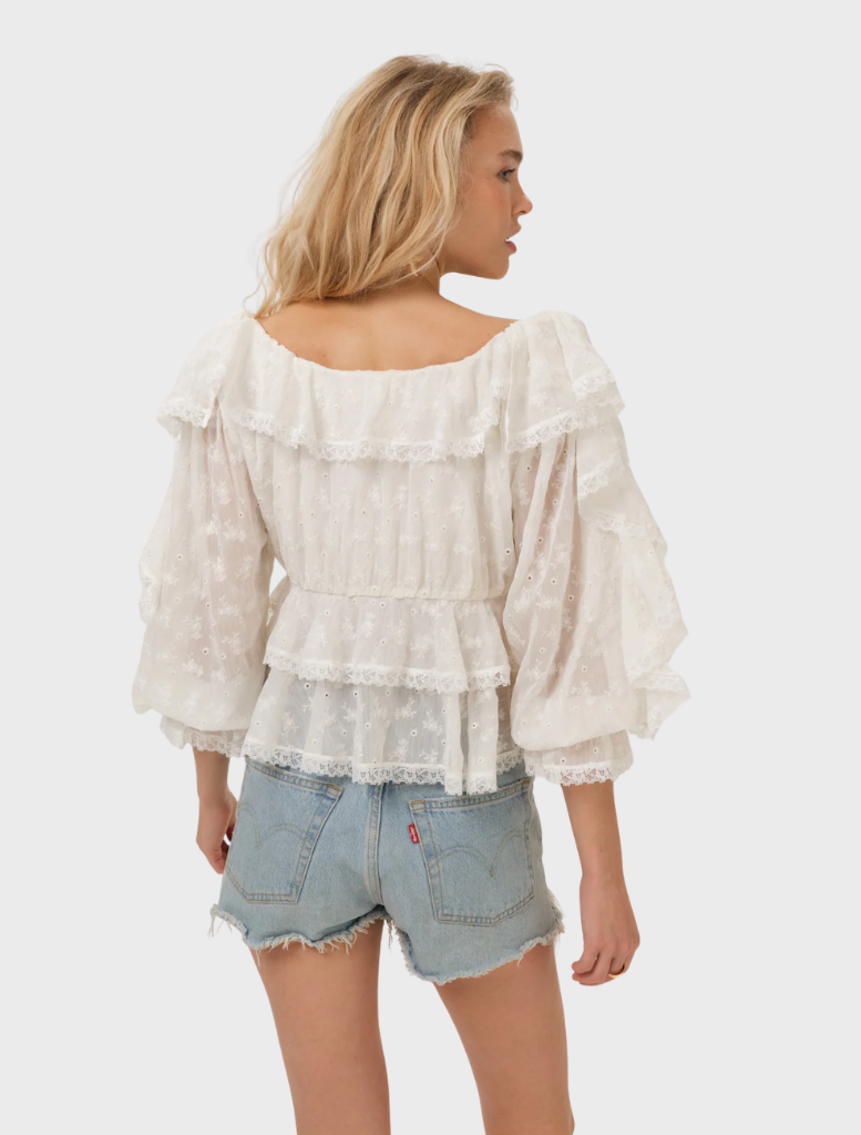 A cream Lilou top hanging, featuring a stylish cut and smooth fabric, ideal for casual or formal wear.
