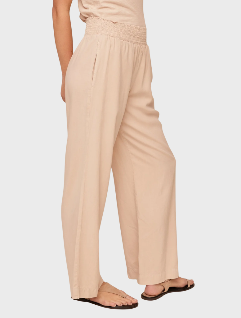 Wide-leg pants with a smocked waist in a soft linen sand color, designed for a comfortable and stylish fit.