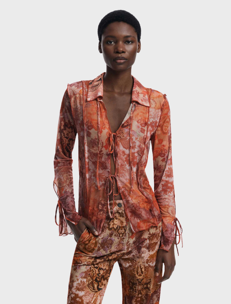 Model wearing a long-sleeve orange and brown paisley print blouse, showcasing a vibrant multi-colored design.