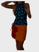 A woman dressed in a blue doted tank top and an orange skirt smiles, embodying a cheerful and fashionable look.