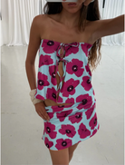 A woman wearing a tank top and skirt stands with her back to the camera, highlighting the vibrant colors of her outfit.