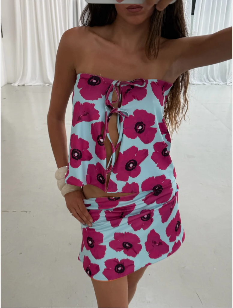 A woman wearing a tank top and skirt stands with her back to the camera, highlighting the vibrant colors of her outfit.