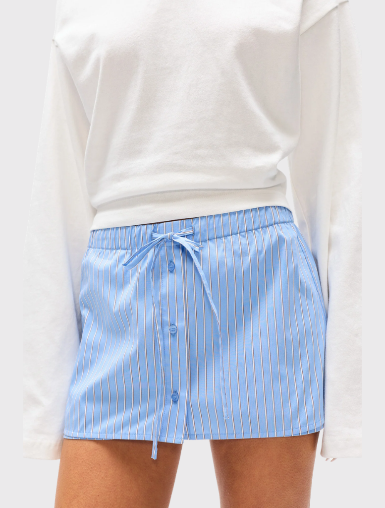 The Margaux Skort showcases a blue stripe design, mini length, built-in shorts, and an elastic waistband for a relaxed fit.