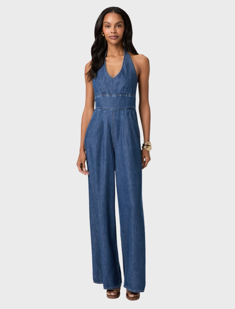 A modern halter-neck jumpsuit in dark wash denim, featuring a wide-leg silhouette and a flattering, drapey fit.