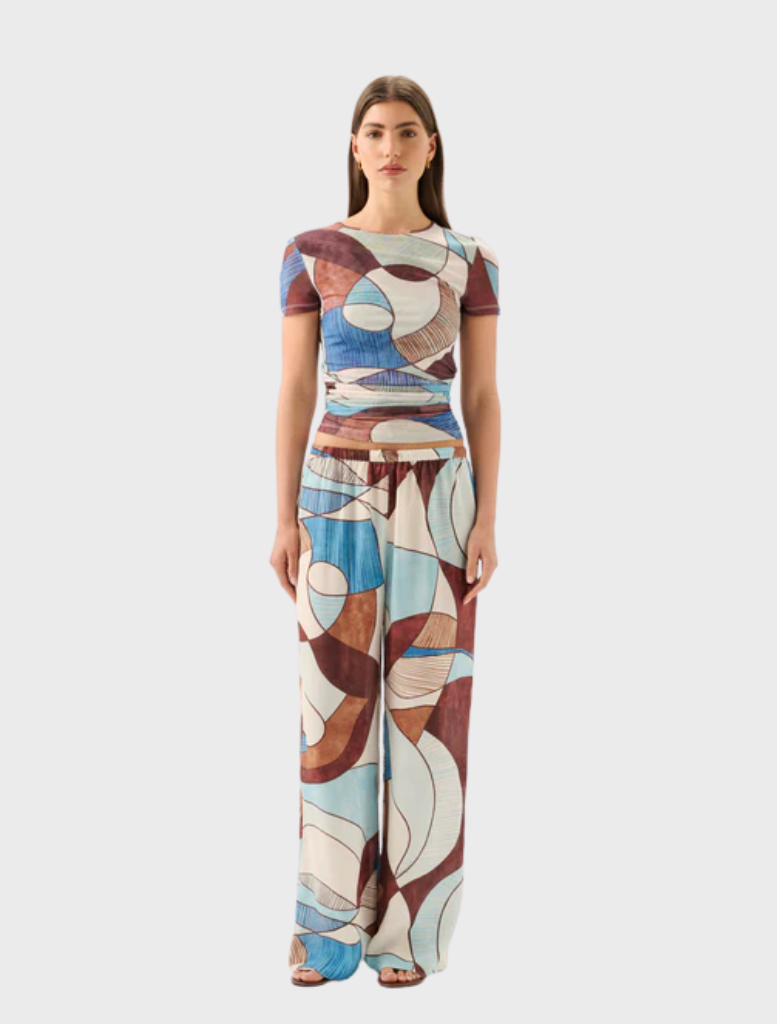 A woman models the Marley Mesh Tee in Playa, featuring vibrant abstract designs on a casual t-shirt.