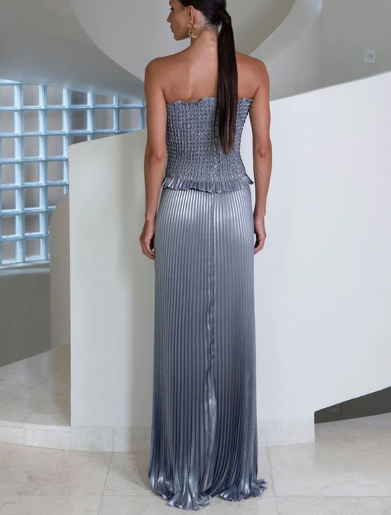 A woman dressed in a metallic gown stands on a stairway, capturing attention with her striking appearance.