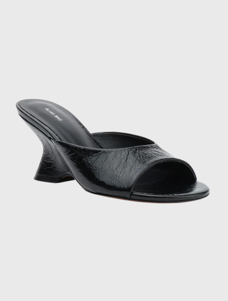 Stylish open-toe mule in black leather, featuring a wide strap, round toe, and a 75mm sculptural wedge heel.
