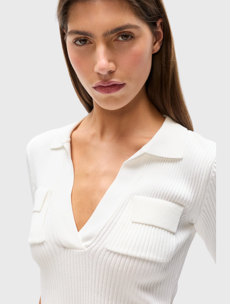Ribbed knit ivory polo with a fitted silhouette, V neckline, short sleeves, and flap pockets on the chest for style.