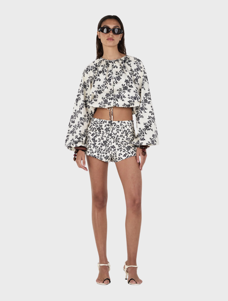 A model displays a white and black floral top along with Jacques Shorts, designed in the Moonlit Vine pattern.
