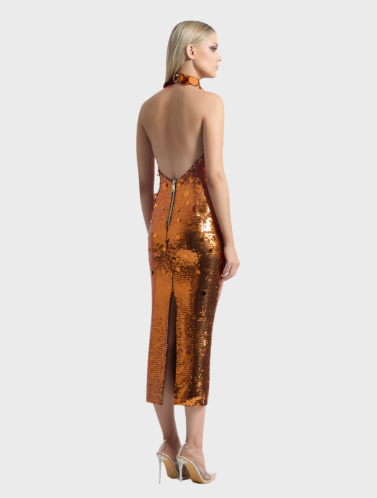 The Area Dress, in vibrant orange, is modeled with a dazzling copper sequinned finish.