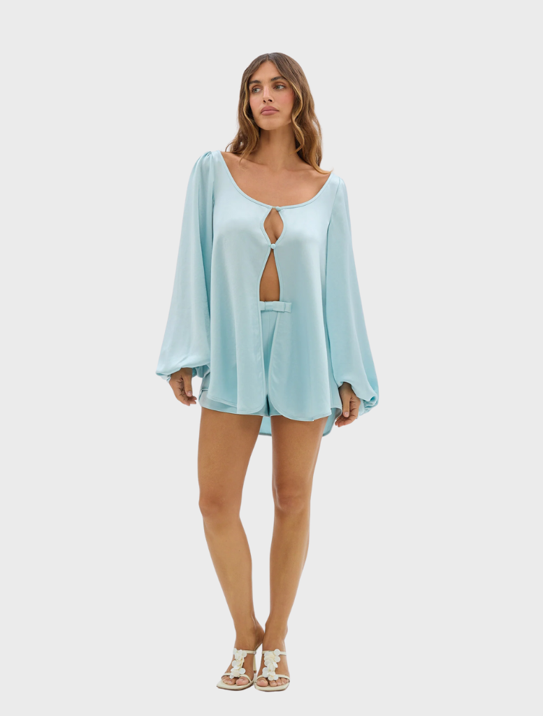 Model showcases a pale blue romper with stylish cutouts, named Penelope Blouse.
