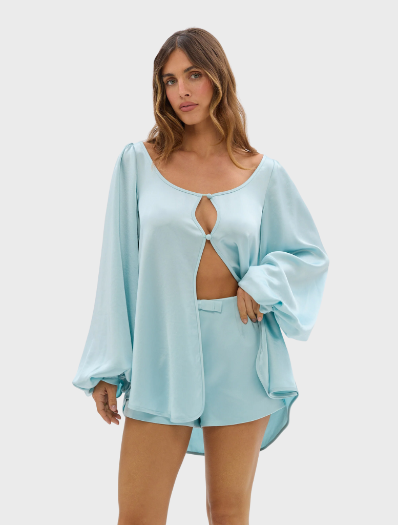 Model wears the Penelope Blouse, a pale blue romper designed with fashionable cutouts.
