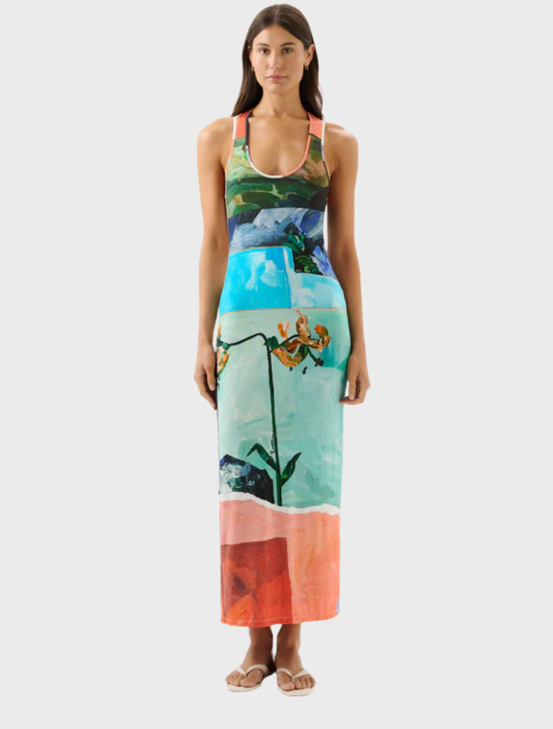 A woman in a vibrant floral dress stands, showcasing a variety of colorful flowers on her attire.