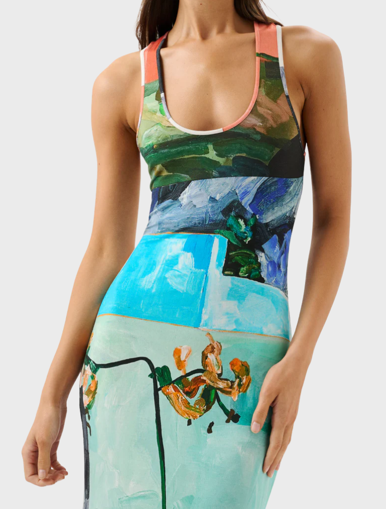 A woman wears a lively dress featuring an array of colorful flowers, exuding a joyful appearance.