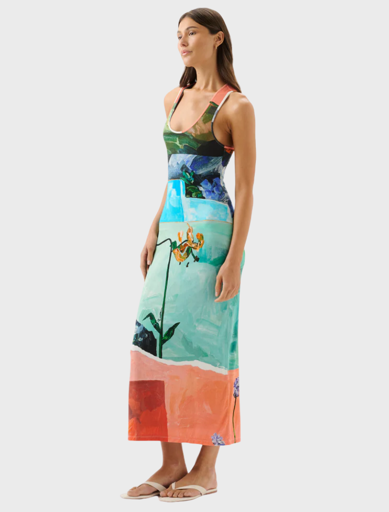 A woman wears a lively dress featuring an array of colorful flowers, exuding a joyful appearance.