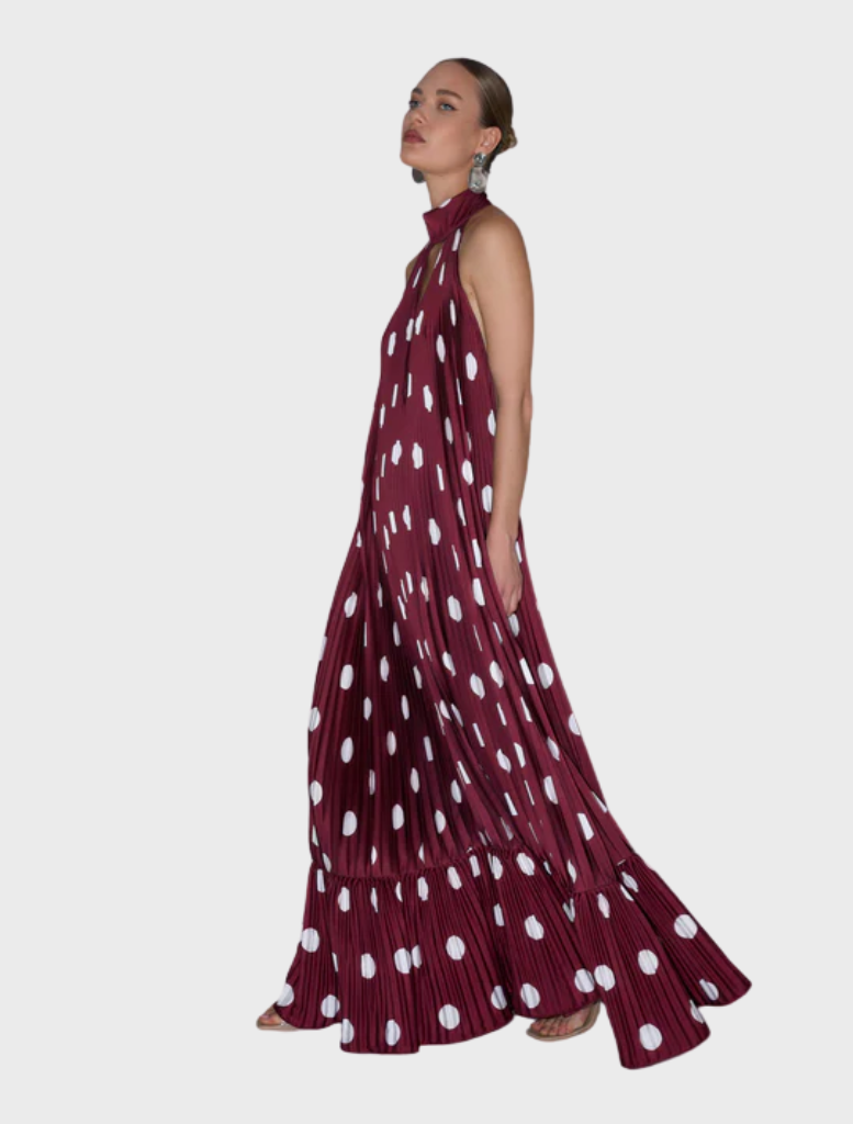 The model is dressed in a maroon polka dot dress, highlighting a playful yet elegant fashion choice.