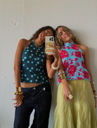 A women captures a selfie, smiling, in front of a clean white wall.