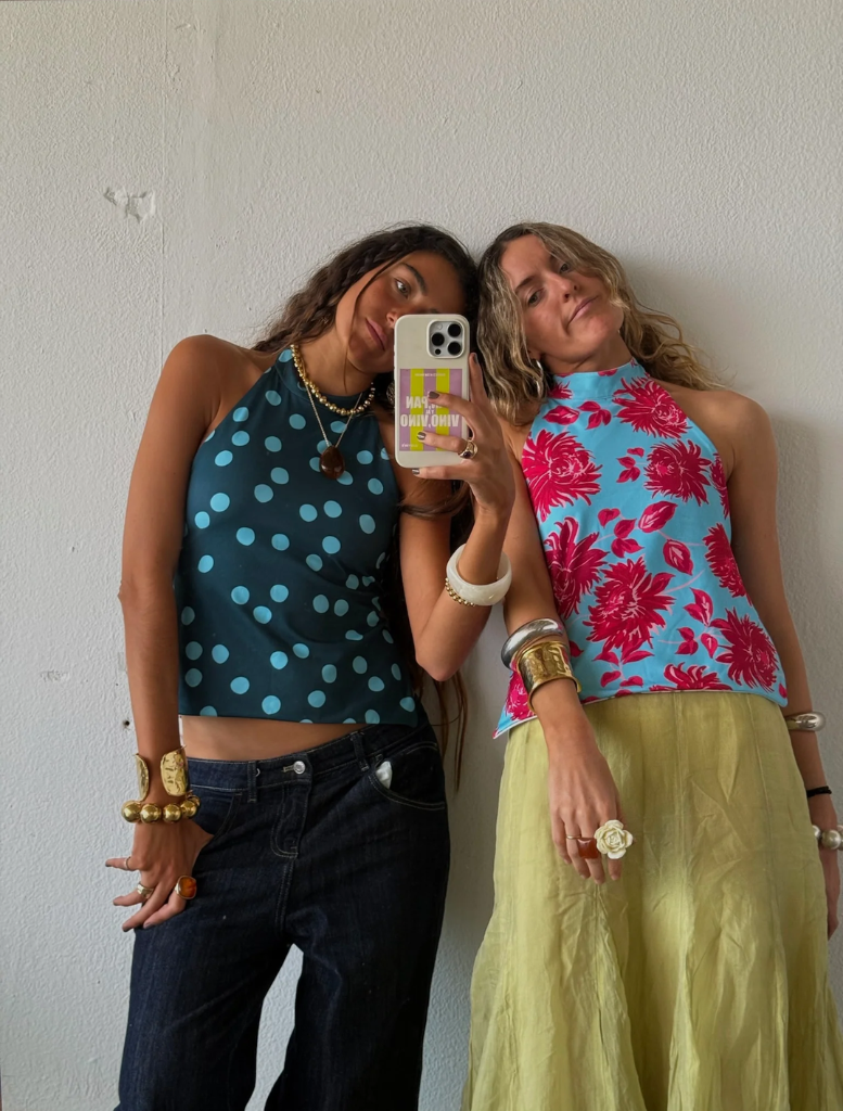 A women captures a selfie, smiling, in front of a clean white wall.